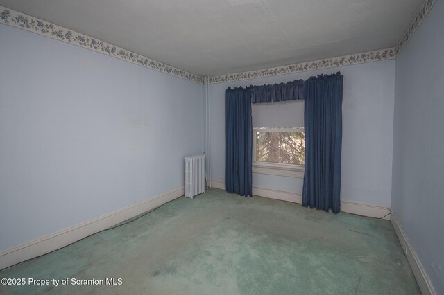empty room with radiator, baseboards, and carpet