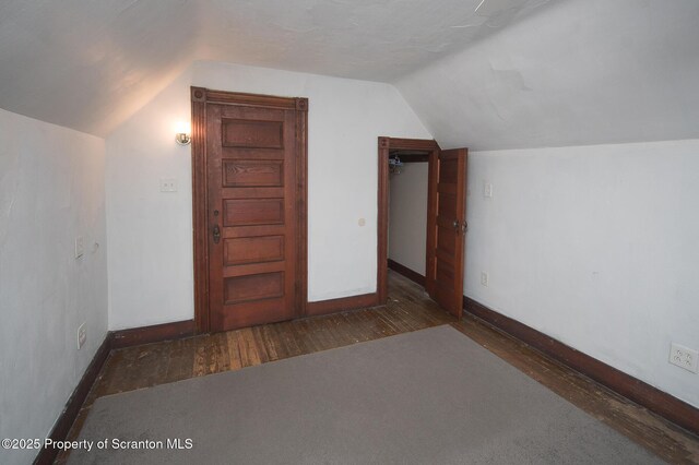additional living space featuring baseboards, lofted ceiling, and wood finished floors