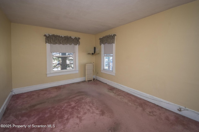 carpeted empty room featuring radiator and baseboards