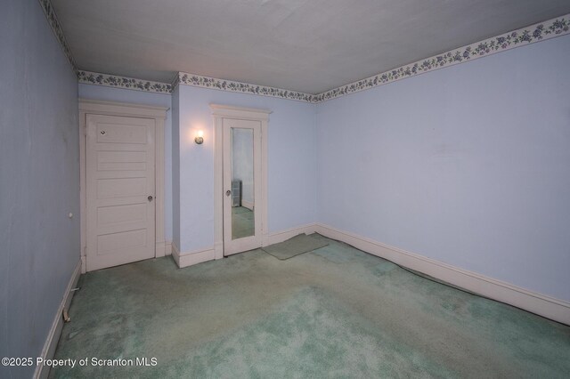 carpeted spare room featuring baseboards