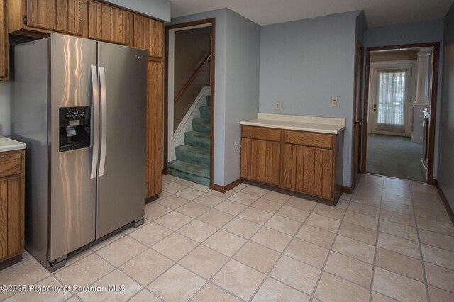 kitchen featuring stainless steel fridge with ice dispenser, light countertops, brown cabinets, and light tile patterned flooring