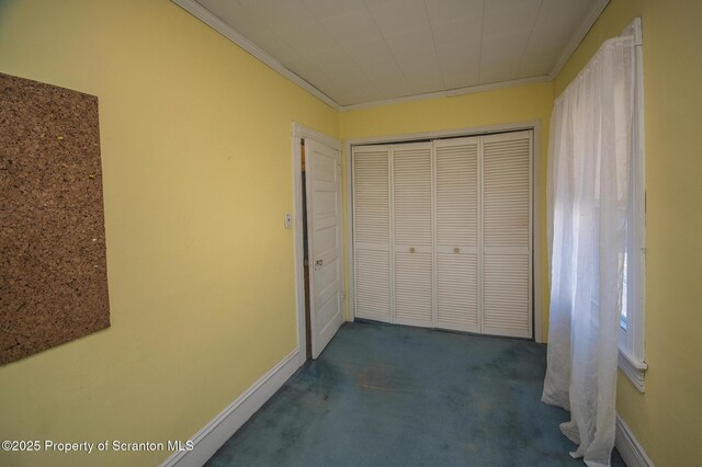 unfurnished bedroom with baseboards, dark carpet, a closet, and crown molding