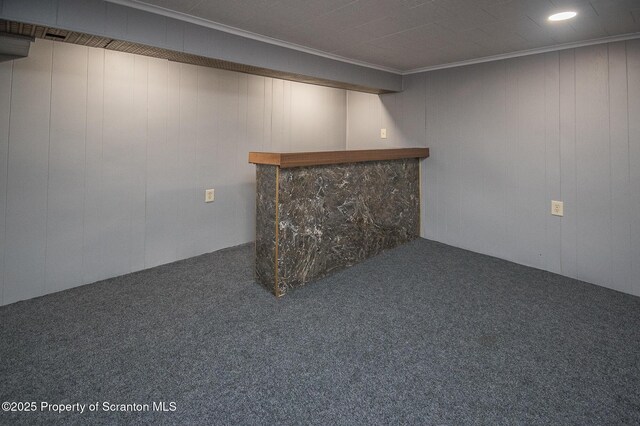 finished basement with a bar, carpet flooring, and crown molding
