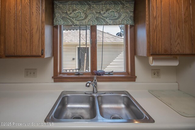 kitchen with light countertops, a sink, and brown cabinets