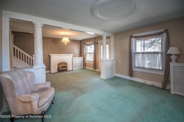 sitting room featuring a brick fireplace, carpet, baseboards, and ornate columns