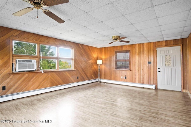 spare room featuring a ceiling fan, a baseboard heating unit, baseboard heating, cooling unit, and wood finished floors