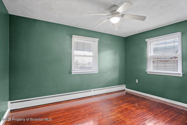 spare room with a baseboard radiator, wood-type flooring, baseboards, and a ceiling fan