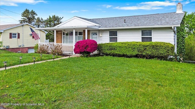view of front of property with covered porch, a chimney, a front yard, and a shingled roof