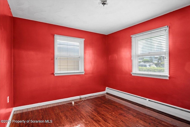 spare room with baseboard heating, baseboards, and wood finished floors
