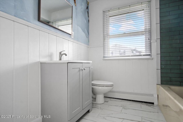 full bathroom featuring a baseboard radiator, marble look tiles, toilet, a bathtub, and vanity