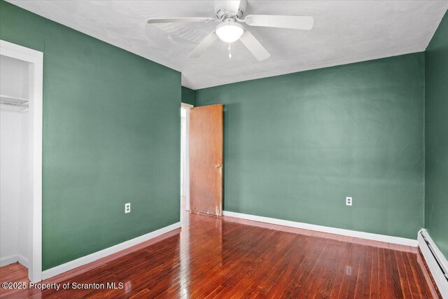 unfurnished bedroom with a baseboard heating unit, baseboards, wood-type flooring, and ceiling fan