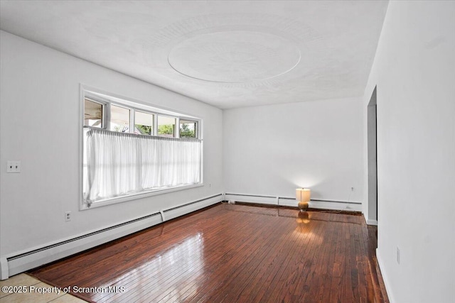 empty room with a baseboard radiator, hardwood / wood-style floors, and baseboards