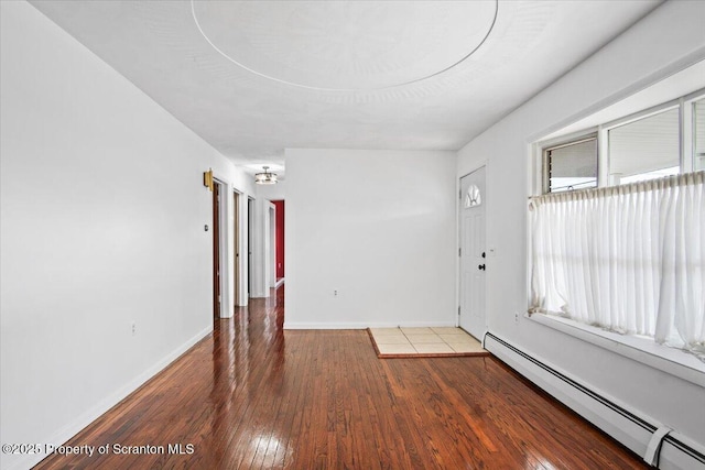 spare room with a baseboard radiator, wood-type flooring, and baseboards