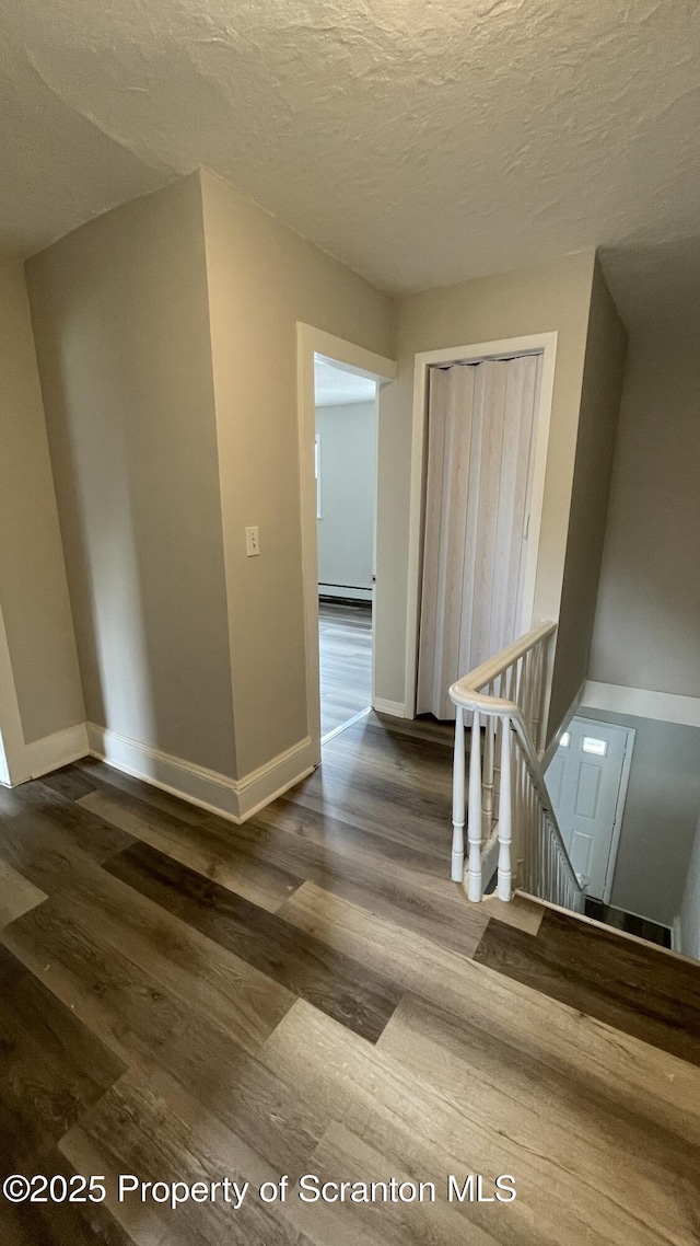 1211 Jackson St 1209-, Scranton, PA 18504 - corridor featuring an upstairs landing, dark wood finished floors, baseboards, a baseboard heating unit, and a textured ceiling