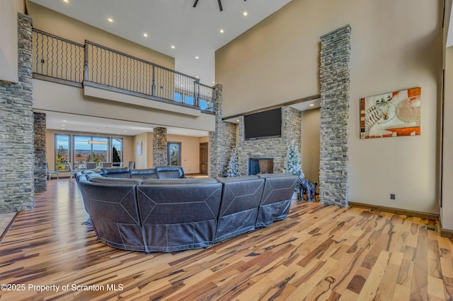 815 Oak St, Archbald, PA 18403 - living room with baseboards, recessed lighting, a stone fireplace, a towering ceiling, and wood-type flooring