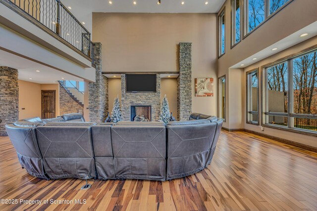 815 Oak St, Archbald, PA 18403 - living area featuring a stone fireplace, wood finished floors, a high ceiling, and a healthy amount of sunlight