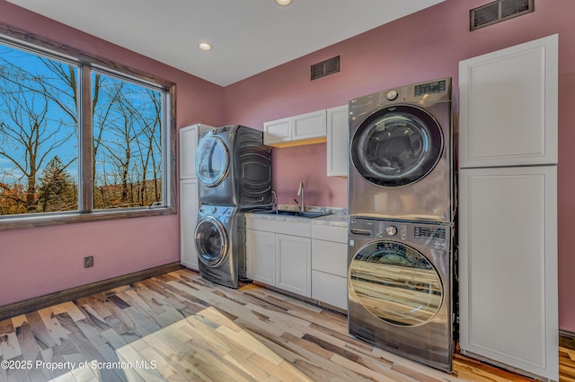 815 Oak St, Archbald, PA 18403 - clothes washing area featuring visible vents, cabinet space, stacked washer and clothes dryer, and light wood finished floors