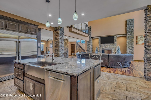 815 Oak St, Archbald, PA 18403 - kitchen with ornate columns, a stone fireplace, dark brown cabinetry, built in fridge, and decorative light fixtures