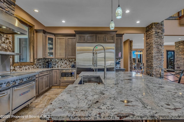 815 Oak St, Archbald, PA 18403 - kitchen featuring light stone counters, glass insert cabinets, built in appliances, pendant lighting, and backsplash