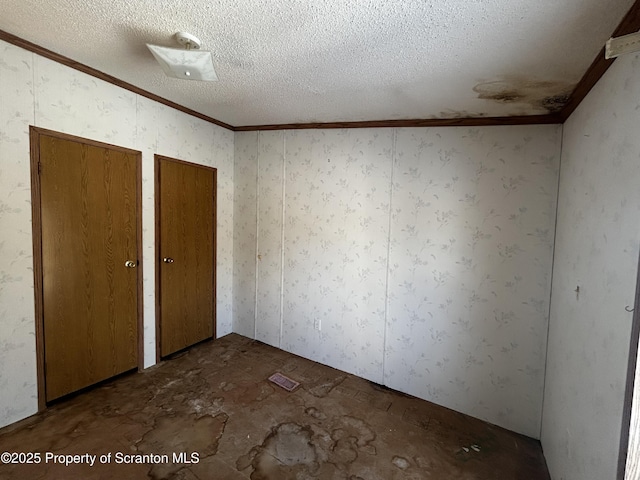 unfurnished bedroom featuring crown molding, a textured ceiling, and two closets