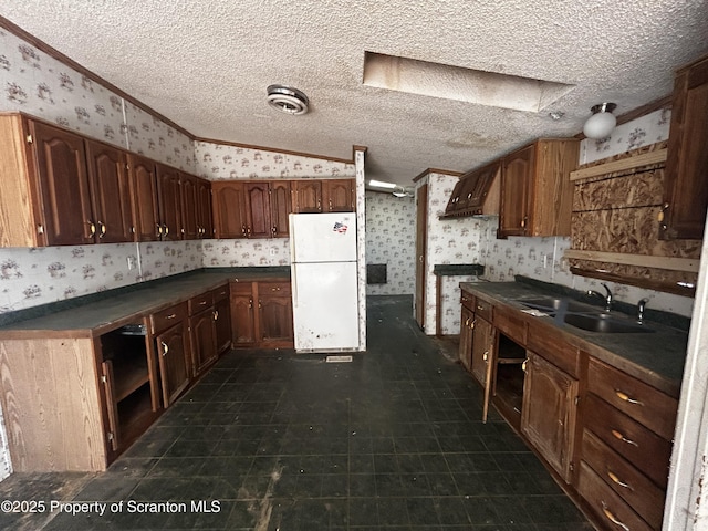 kitchen featuring freestanding refrigerator, dark countertops, and wallpapered walls