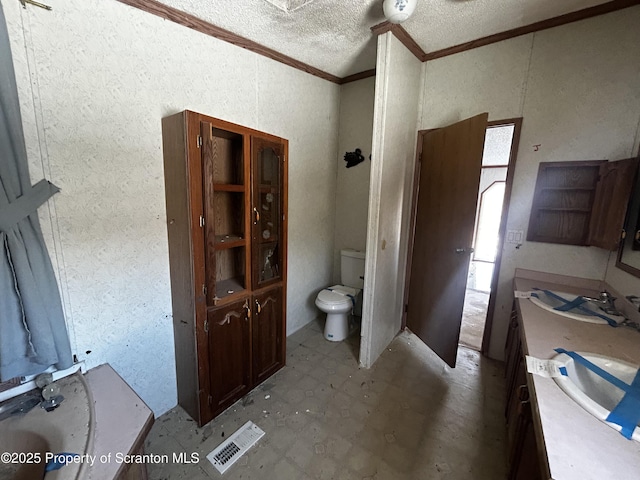 bathroom featuring a textured ceiling, toilet, vanity, ornamental molding, and tile patterned floors