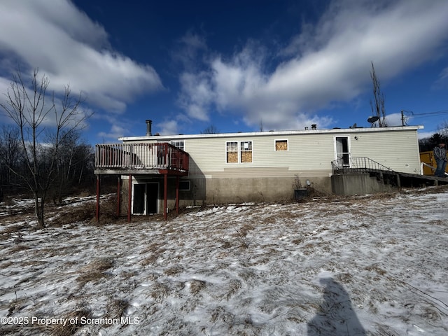 snow covered rear of property featuring a deck