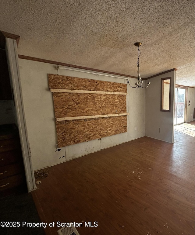 unfurnished dining area featuring an inviting chandelier, crown molding, a textured ceiling, and wood finished floors