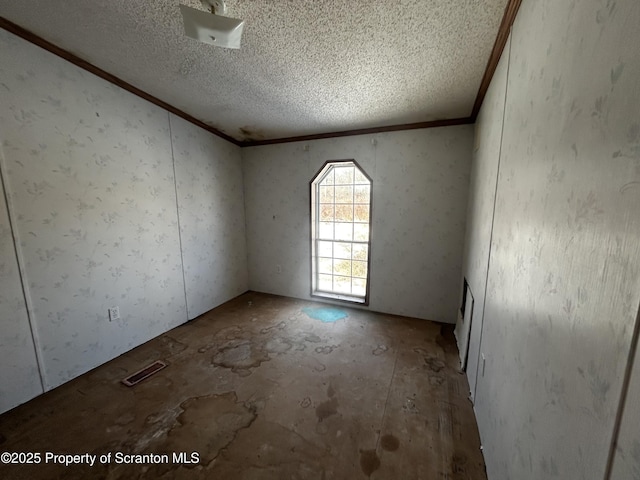 unfurnished room featuring a textured ceiling, visible vents, and crown molding