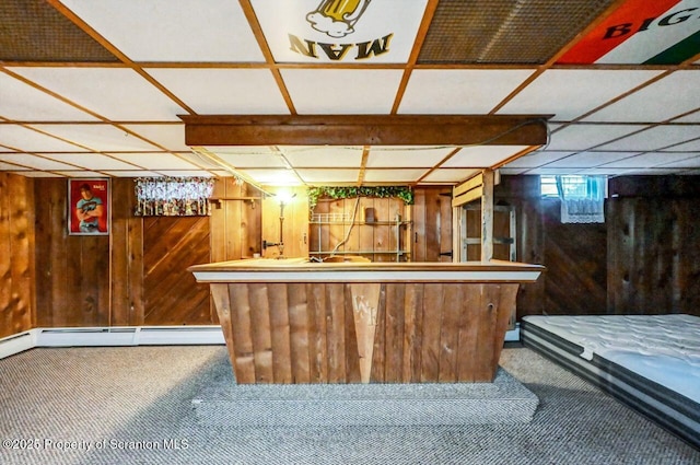 bar featuring a baseboard heating unit, carpet flooring, a drop ceiling, and wooden walls