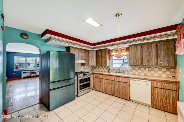 kitchen with appliances with stainless steel finishes, sink, radiator, and backsplash