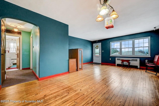 unfurnished living room with radiator heating unit and hardwood / wood-style floors