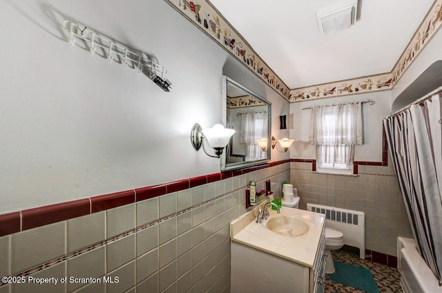 full bathroom featuring radiator, shower / tub combo, tile walls, vanity, and toilet