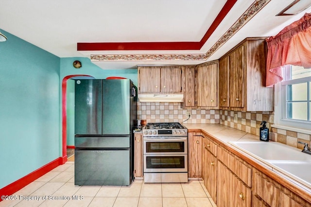 kitchen featuring fridge, decorative backsplash, range with two ovens, and light tile patterned floors