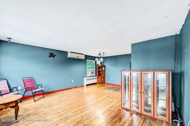 sitting room with a wall mounted air conditioner, radiator, and hardwood / wood-style floors