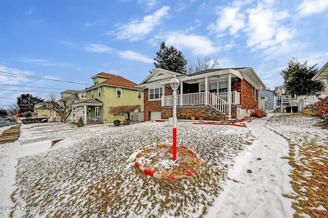 snow covered rear of property with covered porch