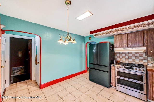 kitchen with black fridge, hanging light fixtures, light tile patterned floors, range with two ovens, and backsplash