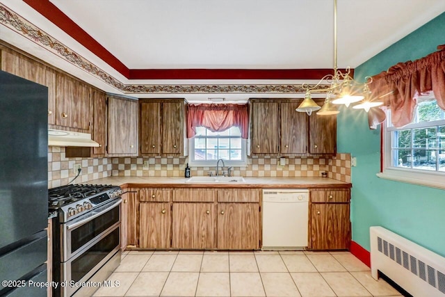 kitchen featuring radiator, sink, white dishwasher, black fridge, and range with two ovens