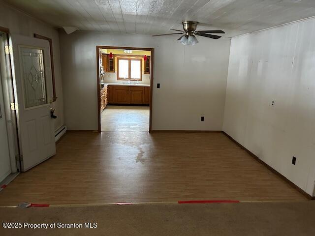 spare room featuring a ceiling fan, a baseboard radiator, and light wood-style flooring