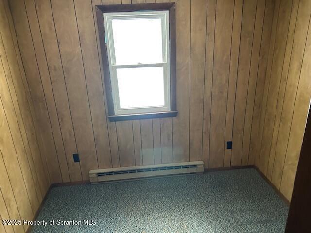 empty room with wooden walls and baseboard heating