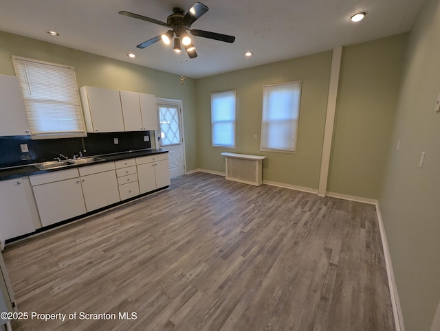 kitchen with sink, white cabinets, decorative backsplash, ceiling fan, and light hardwood / wood-style floors