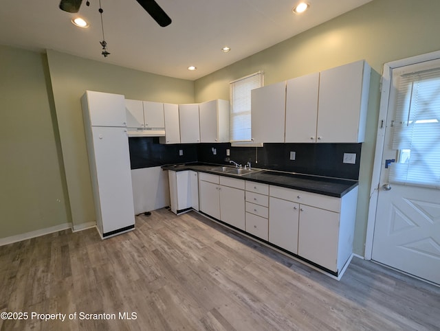 kitchen with sink, backsplash, white cabinets, ceiling fan, and light wood-type flooring