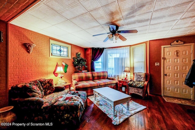 living room featuring dark hardwood / wood-style floors, ceiling fan, and brick wall