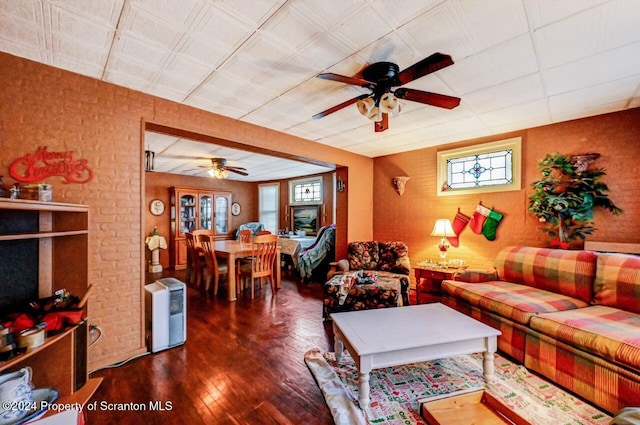 living room featuring ceiling fan, brick wall, and dark hardwood / wood-style floors