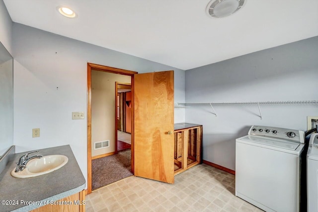 laundry room featuring washing machine and dryer, sink, and light carpet