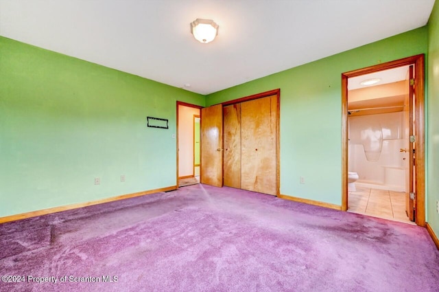 unfurnished bedroom featuring light carpet, ensuite bath, and a closet