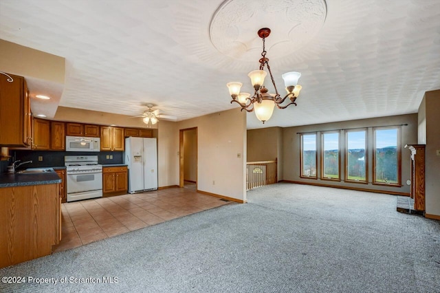 kitchen featuring ceiling fan with notable chandelier, white appliances, light colored carpet, sink, and pendant lighting