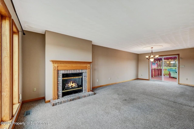 unfurnished living room featuring carpet floors, a chandelier, and a brick fireplace