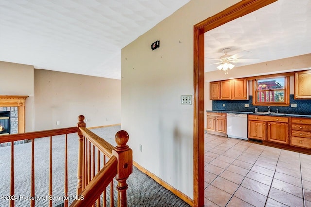 interior space with decorative backsplash, white dishwasher, ceiling fan, sink, and light tile patterned floors