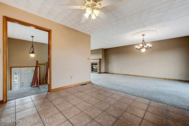 tiled empty room featuring ceiling fan with notable chandelier